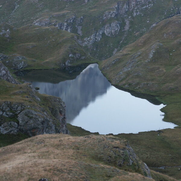 Spiegelglatter Lac de Chanrion, eingebettet in grüne Berglandschaft.