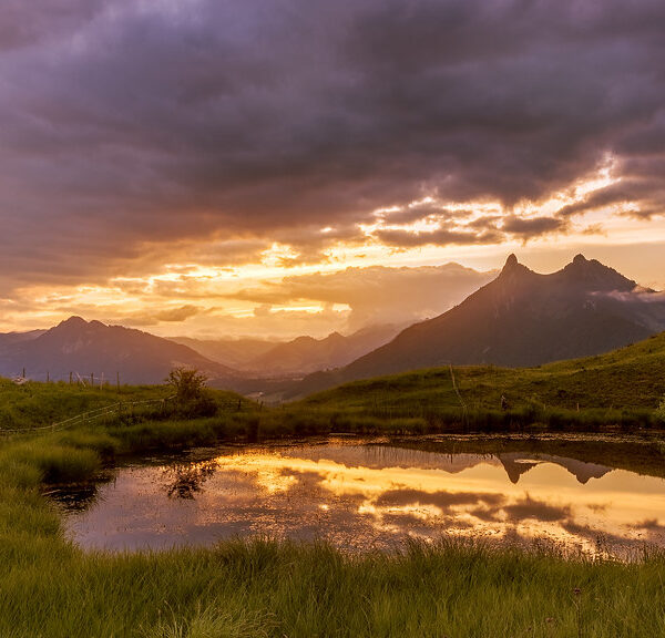 Lac de Mongeron Spiegelung im See bei Sonnenuntergang, grüne Hügel und Berge.