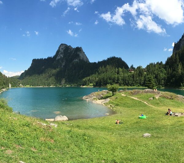 Lac de Tanay: Türkisblauer Bergsee mit grünen Wiesen und bewaldeten Gipfeln.