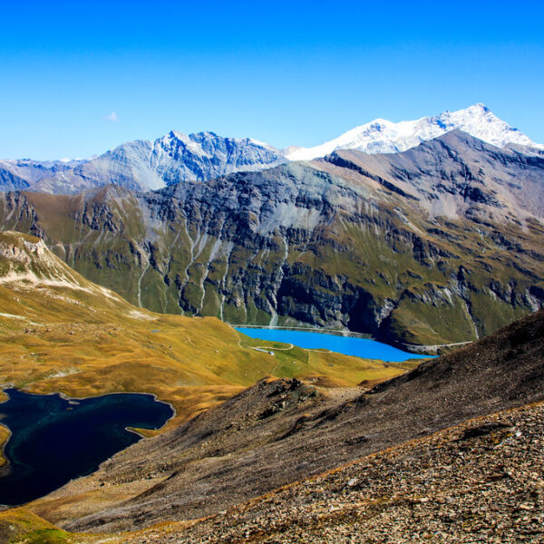 Lac des Autannes: Berglandschaft mit blauem See und schneebedeckten Gipfeln unter blauem Himmel.