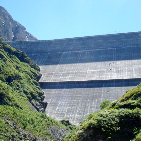 Lac des Dix Staumauer mit grünen Berghängen unter blauem Himmel.