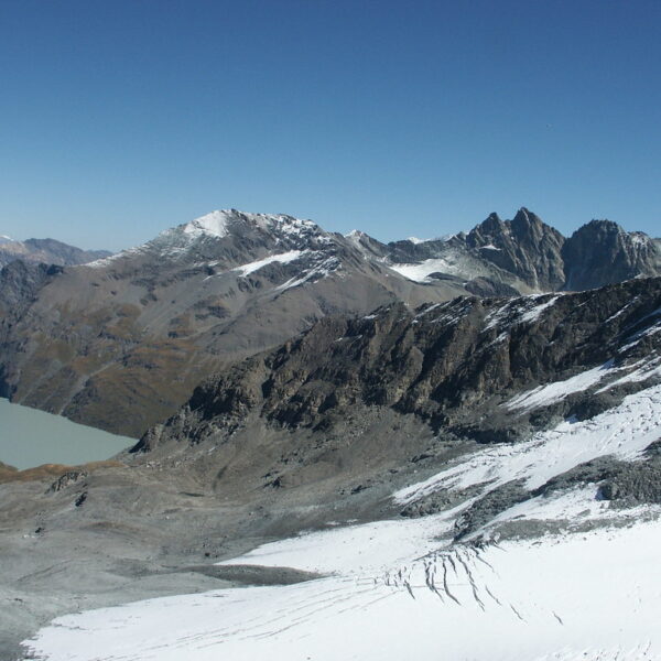 Lac des Dix: Berglandschaft mit See, Schnee und Felsen unter blauem Himmel.
