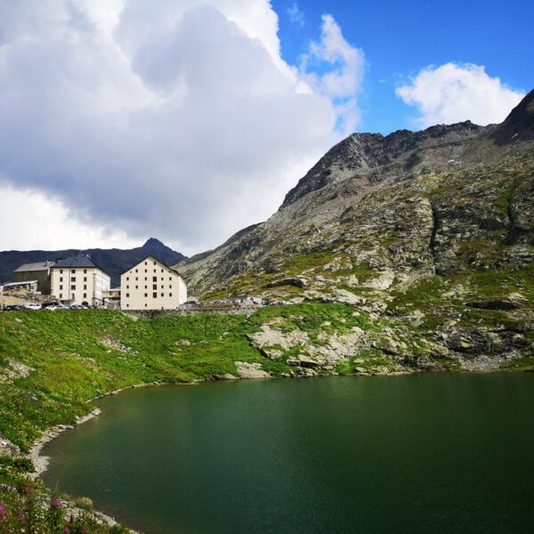 Lac du Grand St. Bernard mit Gebäuden und Bergen unter bewölktem Himmel.