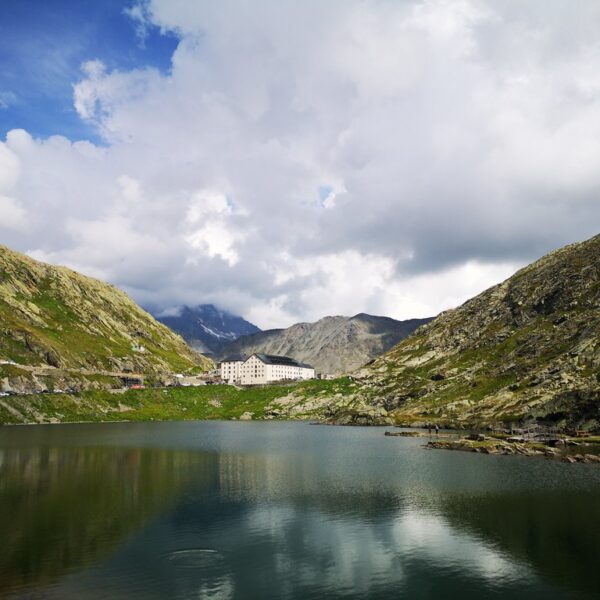 Lac du Grand St. Bernard See mit Hotel und Bergen im Hintergrund, bewölkter Himmel.