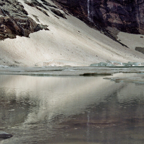 Lagh da Caralin: Eisbedeckter Bergsee mit Schnee und Felsen.