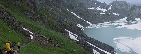 Wanderer am Lago Sfundau mit Schnee bedeckten Bergen.