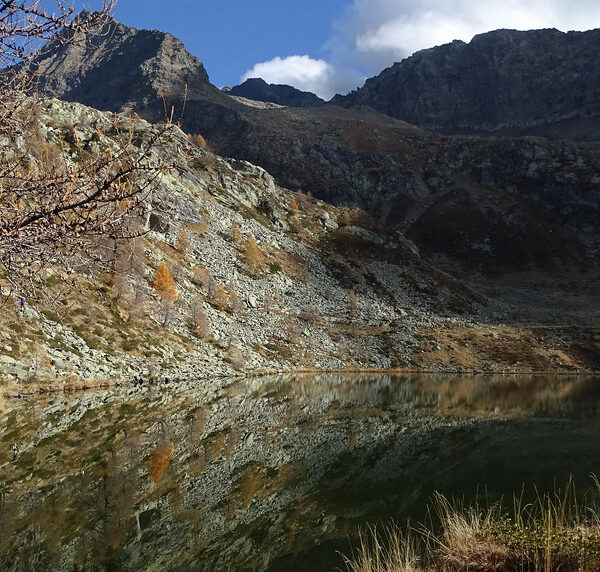 Lago di Mognola Spiegelung mit Bergen und Herbstlandschaft.