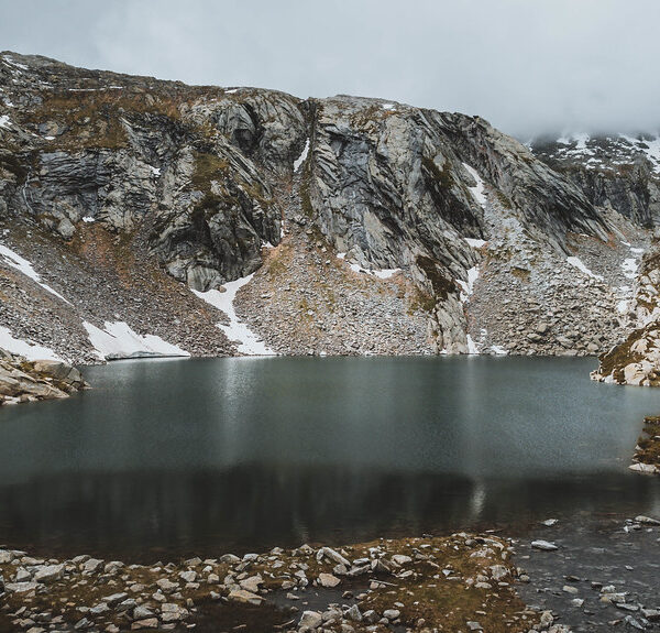 Lago di Sassolo, ein Bergsee umgeben von Felsen und Schnee.
