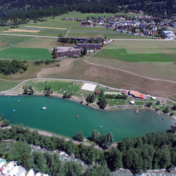 Lai Barnagn Seeansicht mit grüner Landschaft und Gebäuden im Hintergrund.