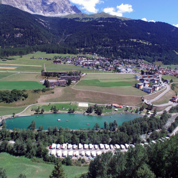 Lai Barnagn: Panoramablick auf See, Campingplatz und Bergdorf in Graubünden.