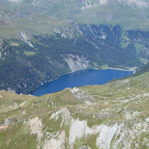 Lai da Marmorera: Blauer Bergsee umgeben von grünen Bergen und Wäldern in der Schweiz.