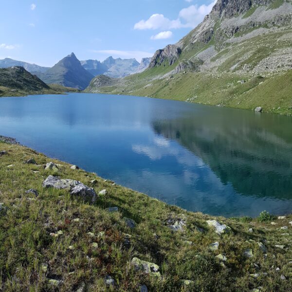 Bergsee in Grevasalvas mit Spiegelung des Himmels und der umliegenden Berge