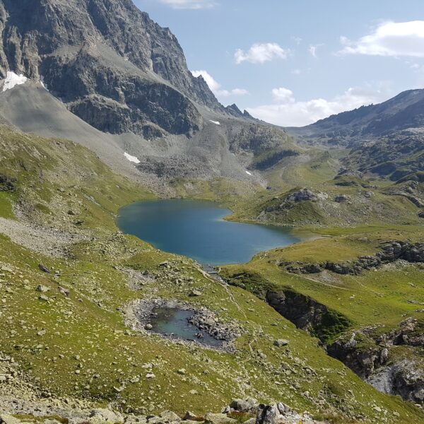 Bergsee Grevasalvas mit grünen Wiesen und felsigen Gipfeln.