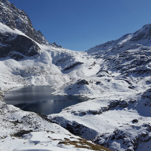 Verschneiter Bergsee Grevasalvas unter blauem Himmel