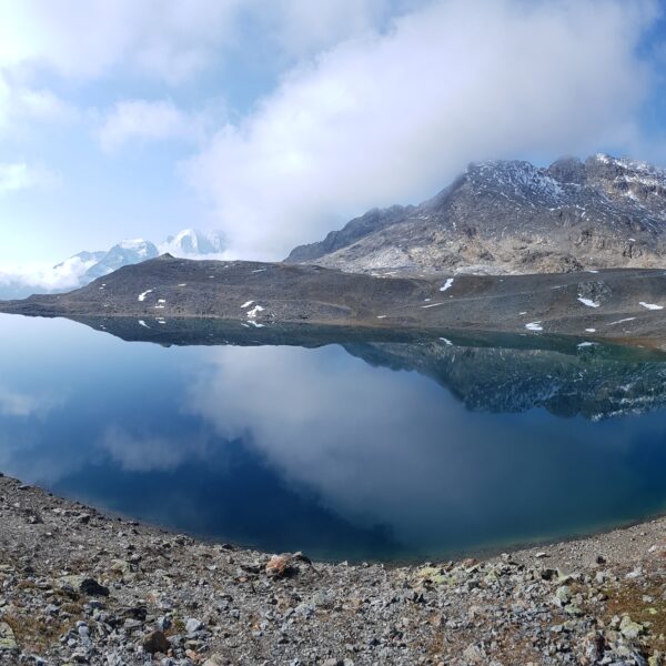 Lej da la Pischa: Bergsee mit Spiegelung des Himmels und schneebedeckten Gipfeln.