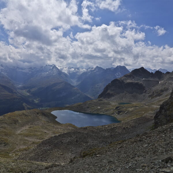 Lej da la Tscheppa: Bergsee in den Alpen mit schneebedeckten Gipfeln unter blauem Himmel.