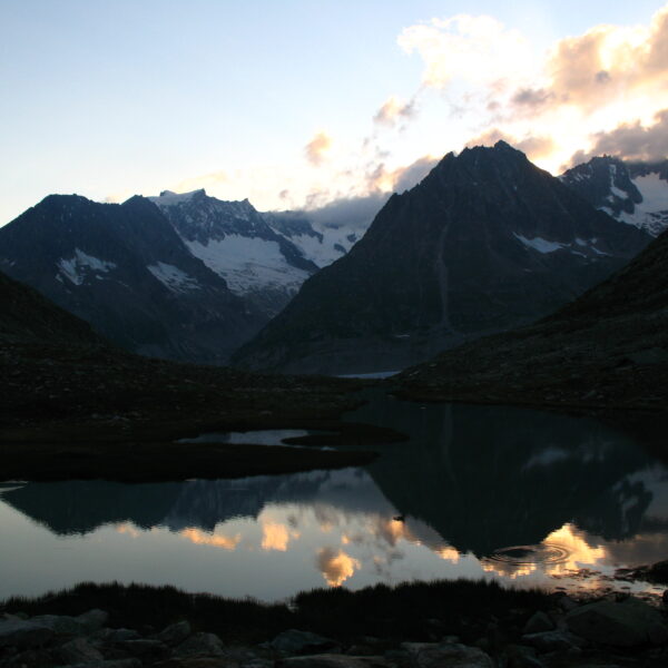 Märjelensee See mit Spiegelung der Berge und Wolken bei Sonnenuntergang.