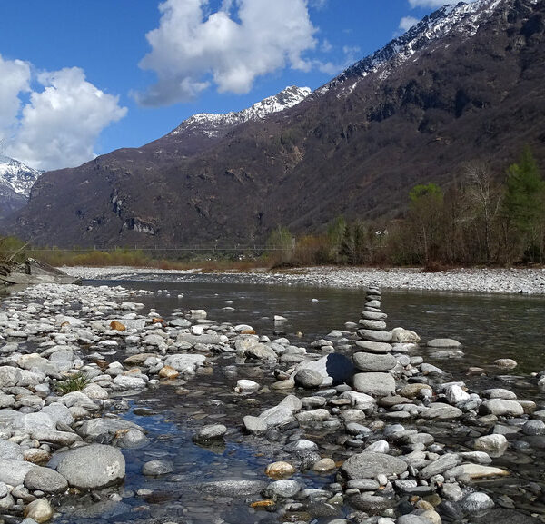 Fluss Maggia mit Steinen im Vordergrund und Bergen im Hintergrund