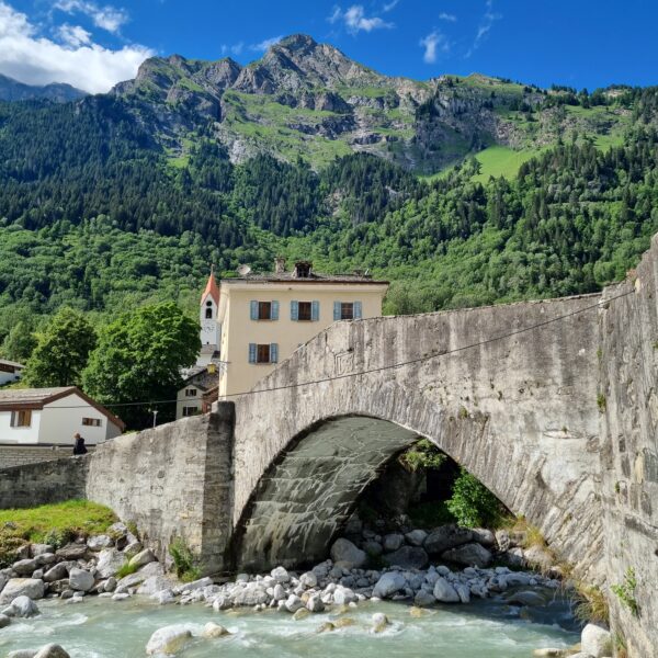 Historische Steinbrücke in Mera, Schweiz, vor Bergkulisse und malerischer Landschaft.