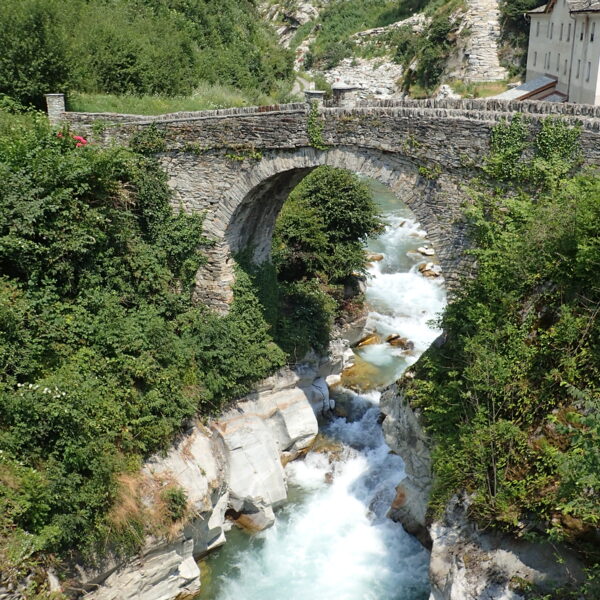 Steinbrücke über den tosenden Fluss Mera in malerischer Landschaft.