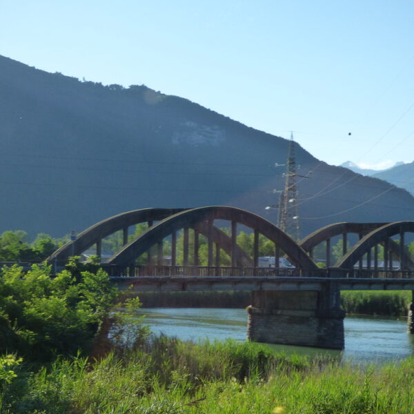 Bogenbrücke über Fluss mit Bergkulisse im Hintergrund