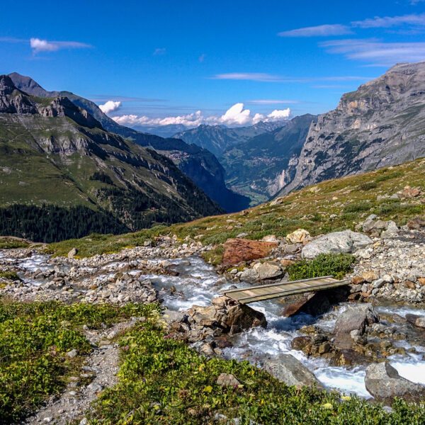Oberhornsee Wanderweg: Bach mit Brücke in den Schweizer Alpen vor Bergkulisse.