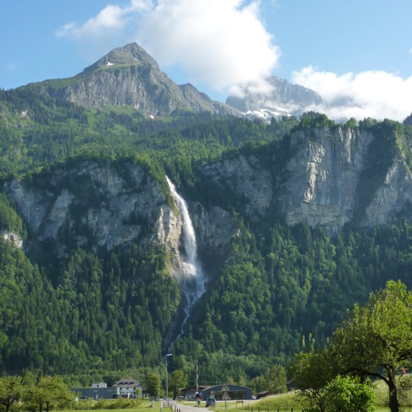 Oltschibach Wasserfall in den Schweizer Alpen, grüne Wiesen und Berge im Hintergrund.