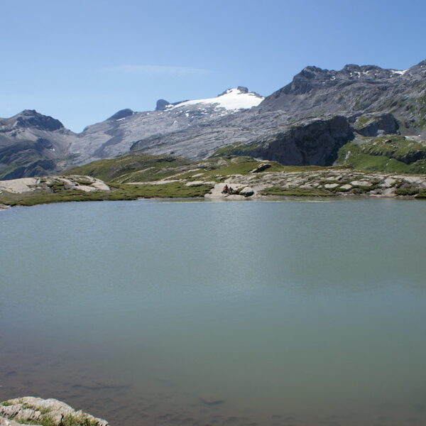 Plan des Roses: Bergsee mit schneebedeckten Gipfeln im Hintergrund.