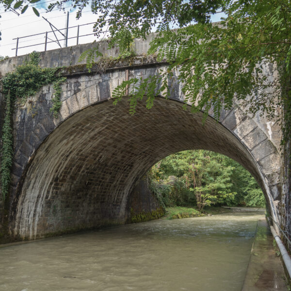 Steinbrücke über einen Fluss in Promenthouse. Bewachsen mit Efeu.