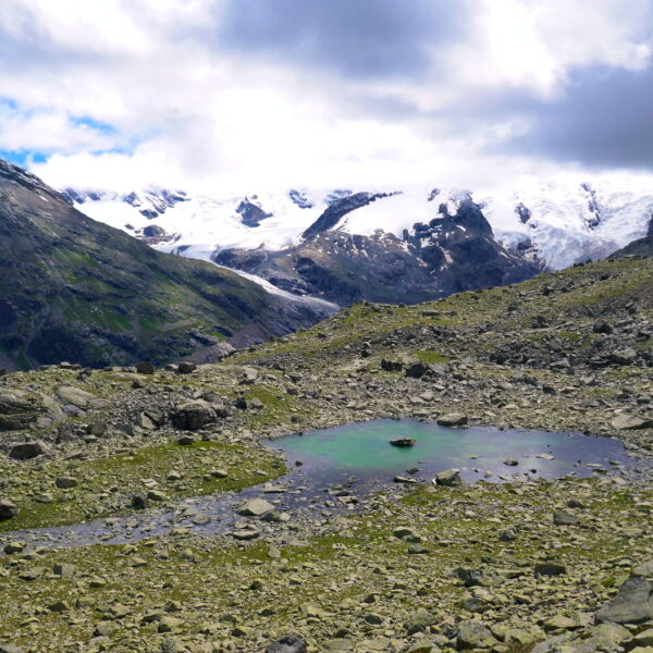 Puoz Bass Bergsee mit schneebedeckten Bergen im Hintergrund.