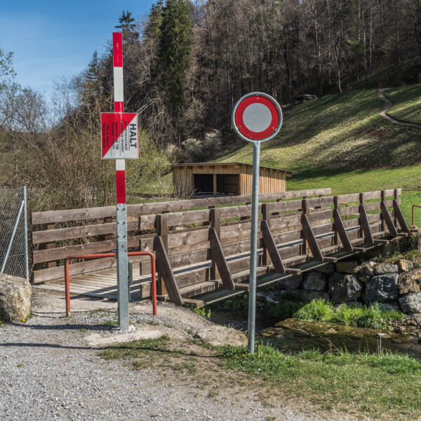 Holzbrücke über den Reppischbach mit Haltestellenschild und Verbotsschild.