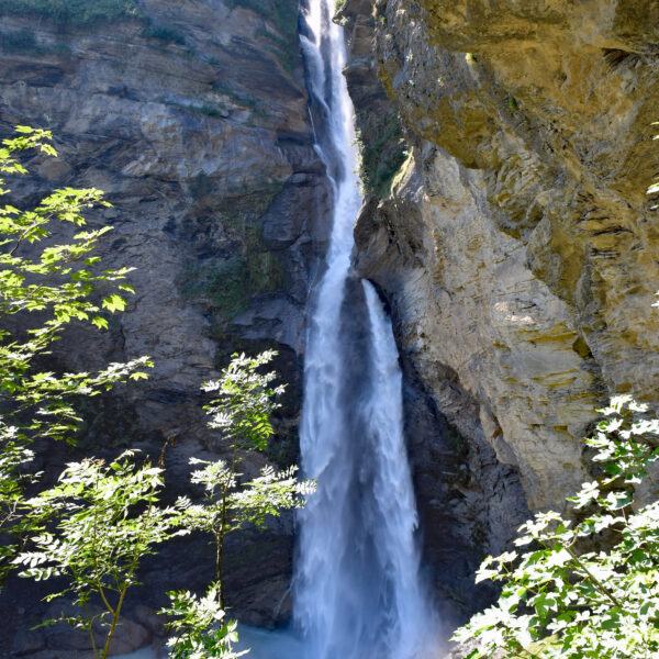 Rychenbachfall: Hoher Wasserfall in den Schweizer Alpen mit Wanderern am Fuß des Wasserfalls.
