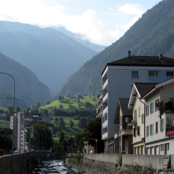 Saltina Fluss in Brig, Schweiz, mit Gebäuden und Bergen im Hintergrund.