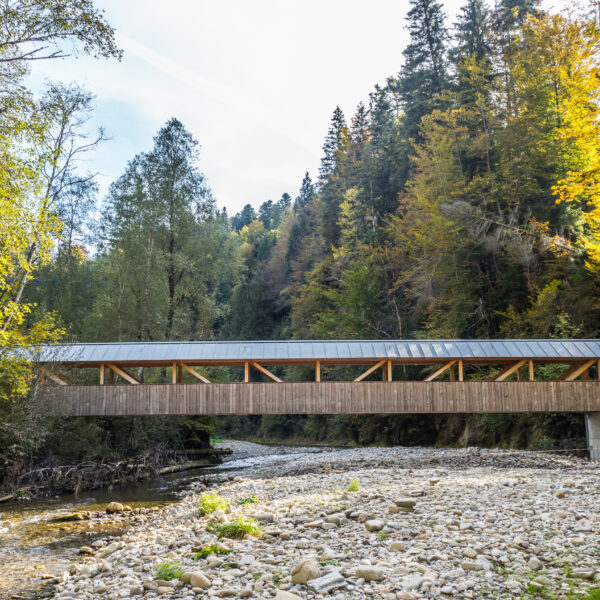 Gedeckte Holzbrücke über den Fluss Schwarzwasser, umgeben von Herbstbäumen.