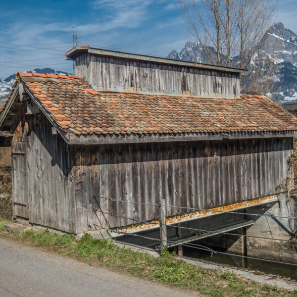 Alte Holzmühle in Seeweren, Schweiz, mit Bergpanorama im Hintergrund.