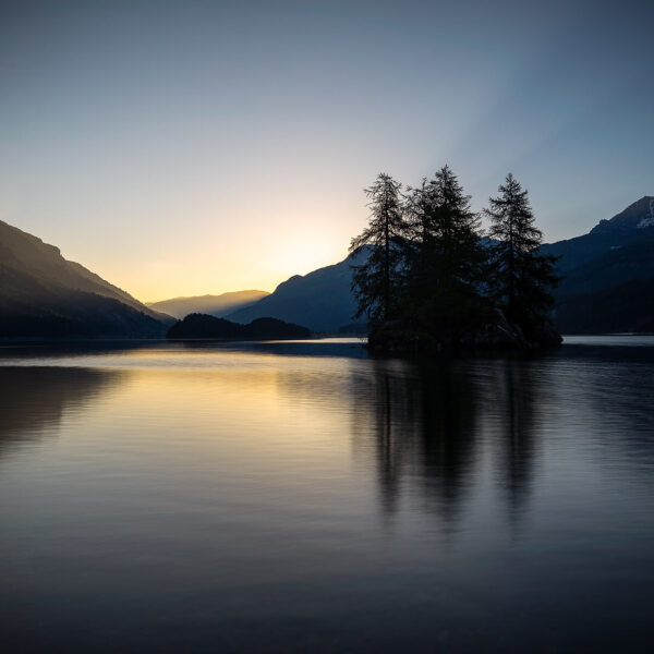 Silsersee bei Sonnenaufgang mit Bäumen auf einer kleinen Insel. Lej da Segl.