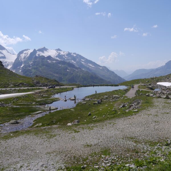 Steinsee in den Schweizer Alpen mit schneebedeckten Bergen und blauem Himmel.