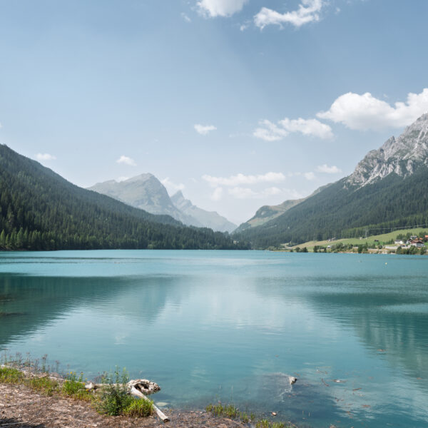 Sufnersee: Ruhiger Bergsee mit bewaldeten Hängen und schneebedeckten Gipfeln im Hintergrund.