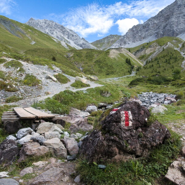 Tiejerbach Wanderweg mit Brücke und rot-weißem Wegzeichen in den Bergen.