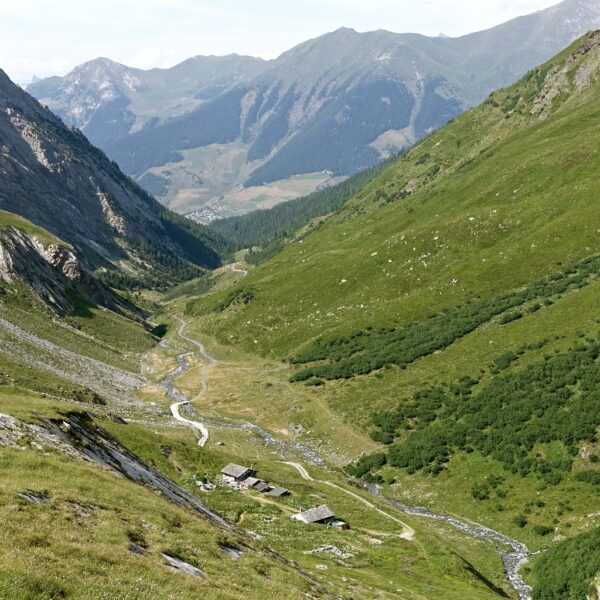 Tal im Torrent de l'A mit grünen Hängen, Bach und Berghütten.