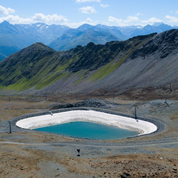 Totalpsee Bergsee in den Alpen, umgeben von Bergen und Skipisten. Blauer Himmel.