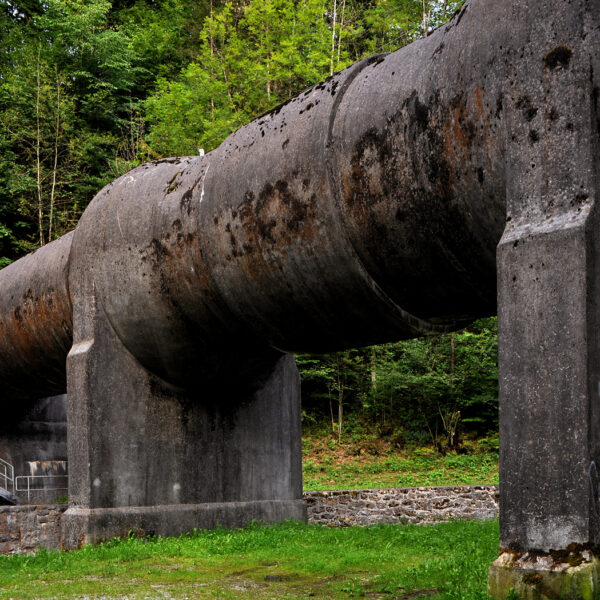Große, alte Rohrleitung auf Betonpfeilern in Trepsenbach, umgeben von Wald.