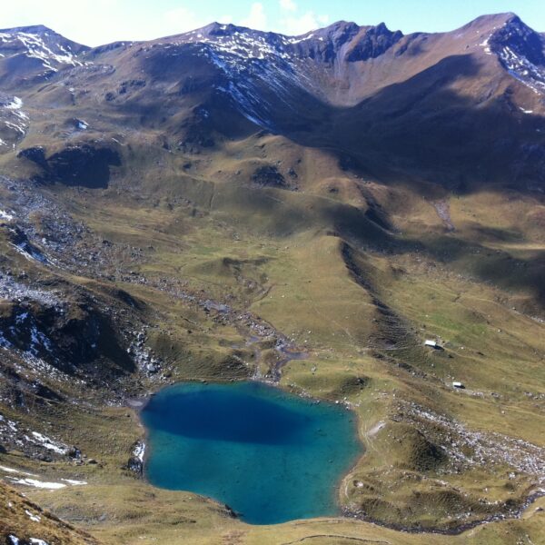 Urdensee, ein Bergsee in den Alpen mit schneebedeckten Gipfeln im Hintergrund.