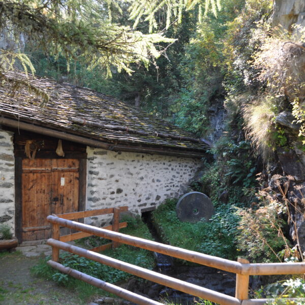 Alte Steinmühle in Valsorey, umgeben von üppiger Vegetation und einem kleinen Bachlauf.