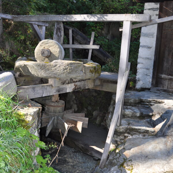 Alte Wassermühle in Valsorey mit Mühlstein und Holzkonstruktion am Bach.