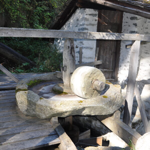 Alte Steinmühle in Valsorey, umgeben von rustikaler Holzkonstruktion und einem kleinen Gebäude.