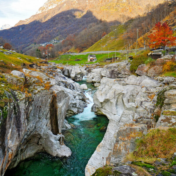 Verzasca-Tal: Türkisgrüner Fluss durch Felsen mit Berg im Hintergrund.