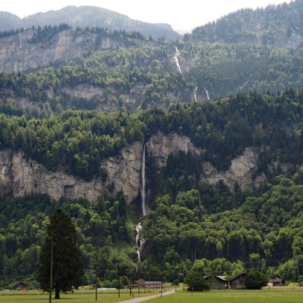 Wandelbach Wasserfall stürzt über eine Felswand in einer grünen Schweizer Landschaft.